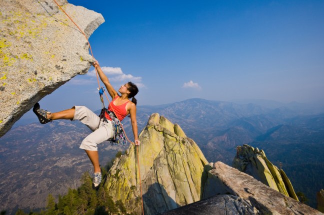 Female rock climber rappelling.